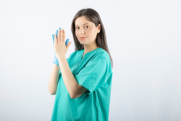 Female doctor in medical gloves showing hands on white. 