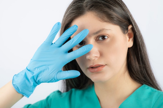 Female doctor in medical gloves showing hands on white. 
