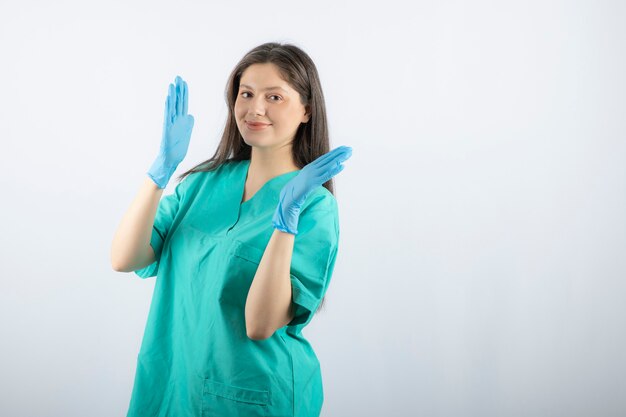 Female doctor in medical gloves showing hands on white. 