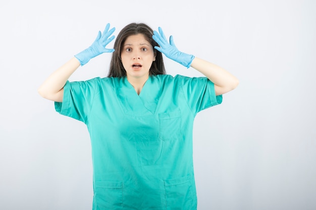 Female doctor in medical gloves showing hands on white. 