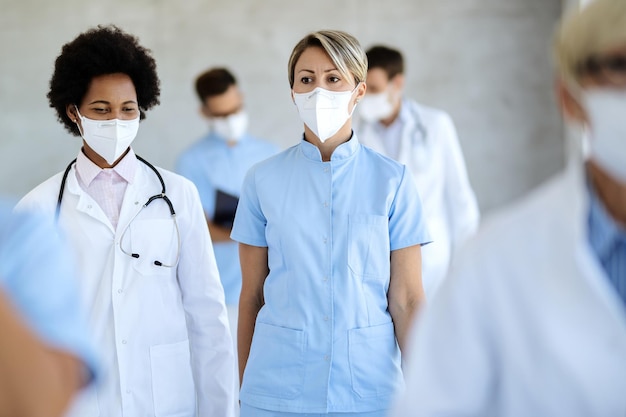 Female doctor and nurse with face masks walking though a
corridor at the hospital