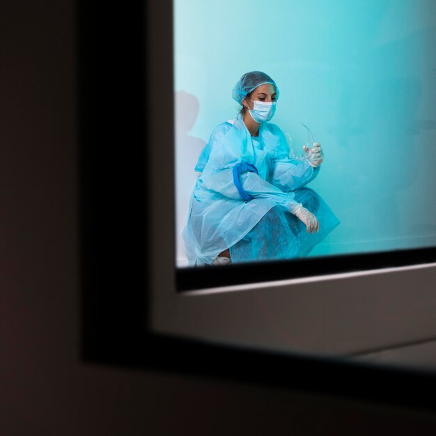 Female doctor in pandemic equipment sitting in the hospital tired