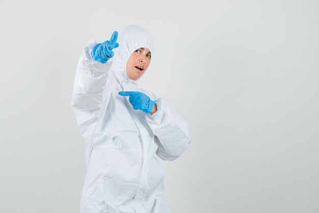 Female doctor pointing at camera and to the side in protective suit