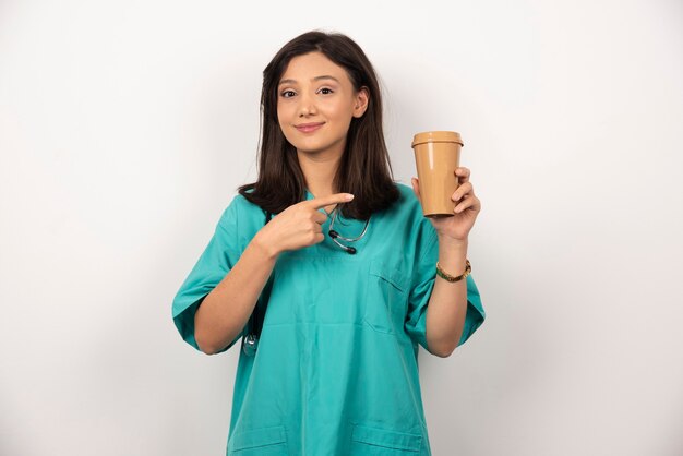 Female doctor pointing cup of coffee on white background. High quality photo