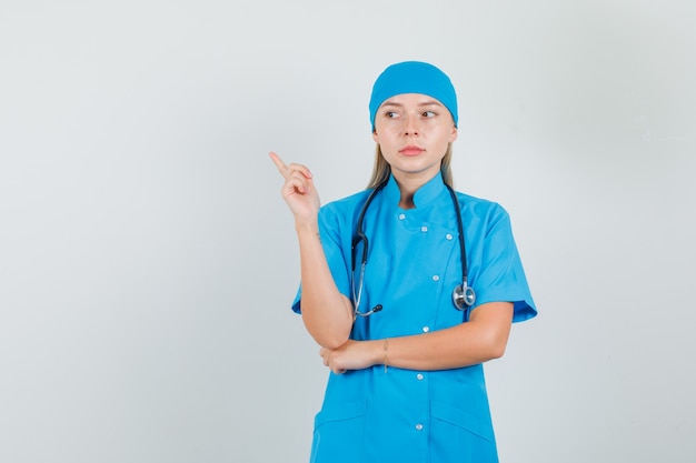 青い制服を着て考えながら人差し指を向ける女医師
