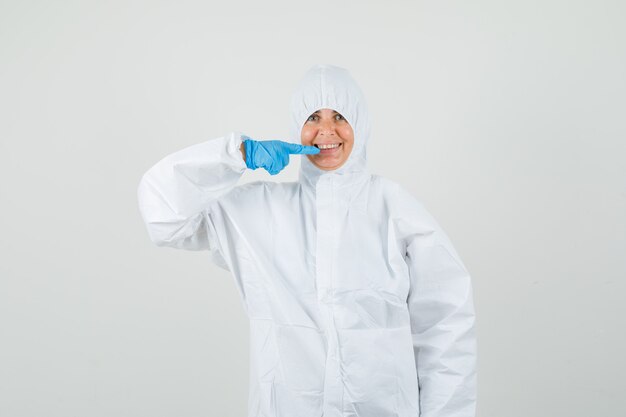 Female doctor pointing at her teeth in protective suit