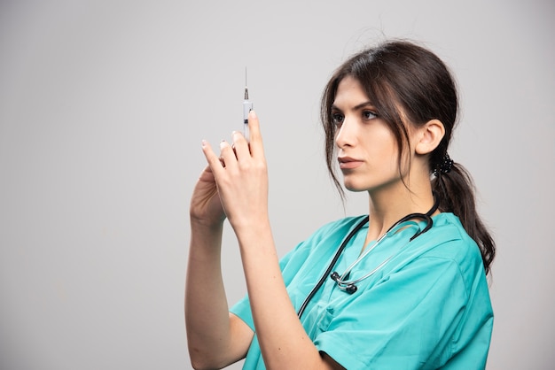 Free photo female doctor preparing for injection on gray