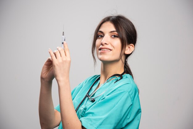 Female doctor preparing for injection on gray