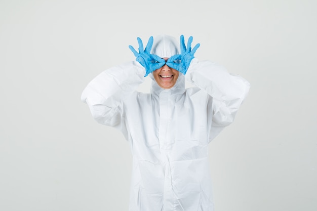 防護服を着た女性医師、眼鏡のジェスチャーを示し、面白がって見える手袋