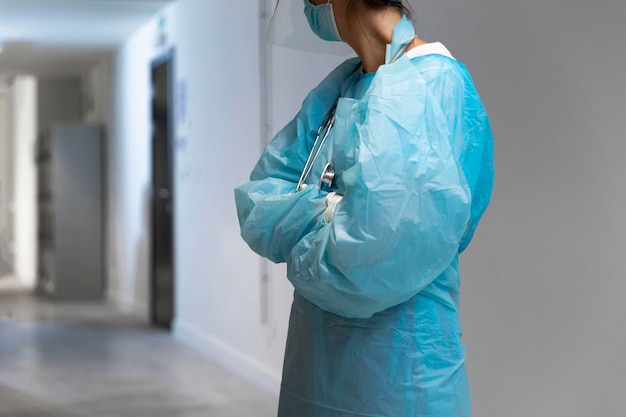 Женщина-врач в защитной одежде смотрит в коридор