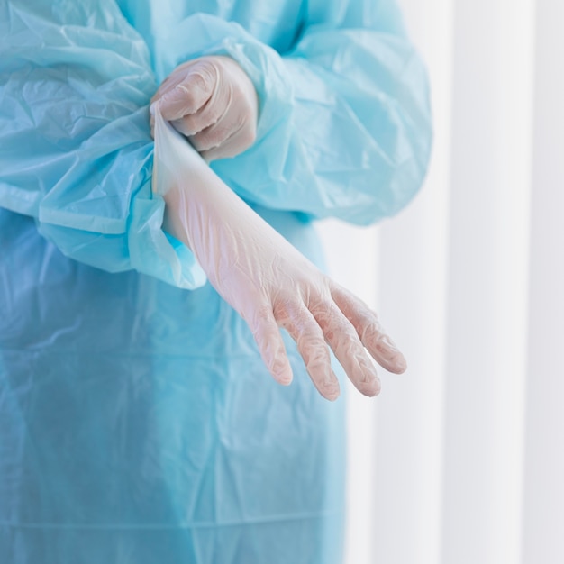Женщина-врач надевает хирургические перчатки