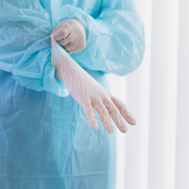 Female doctor putting on surgical gloves