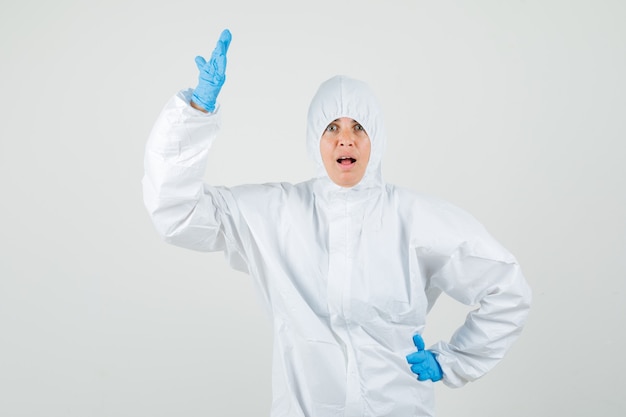 Female doctor raising hand in puzzled gesture in protection suit