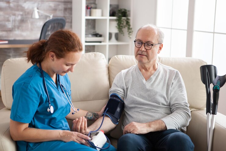 Free Photo female doctor reading blood pressure of old man in nursing home using digital device. nurse and patient sitting on couch.