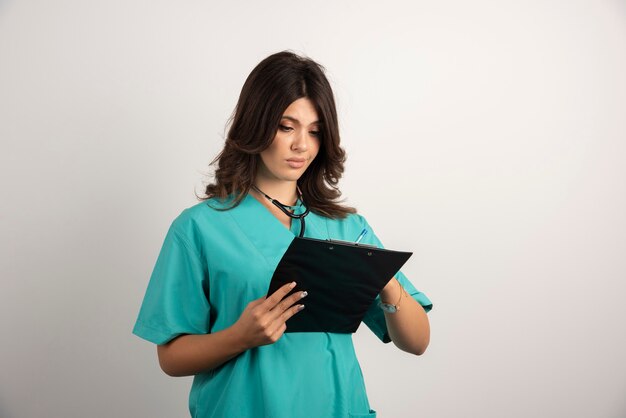 Female doctor reading notes from clipboard