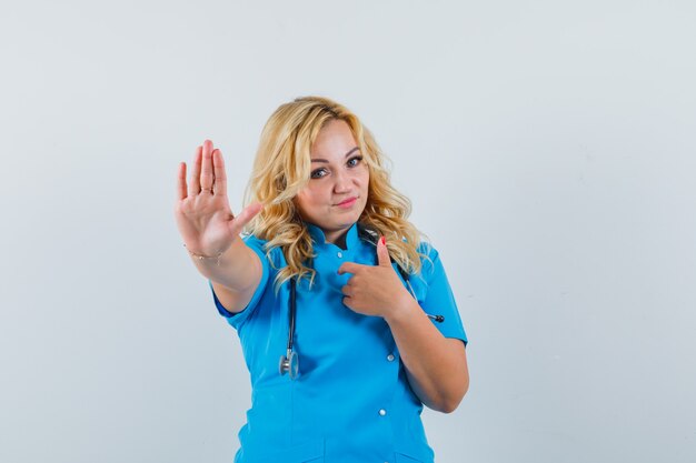 Female doctor rejecting something in blue uniform and looking serious.