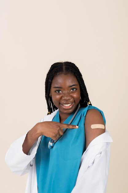백신 접종 후 스티커로 팔을 보여주는 여성 의사
