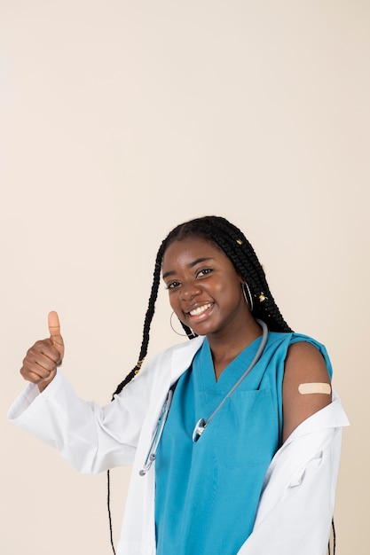 Female doctor showing arm with sticker after getting a vaccine