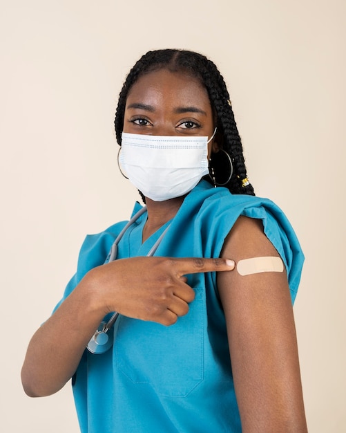 Free photo female doctor showing arm with sticker after getting a vaccine