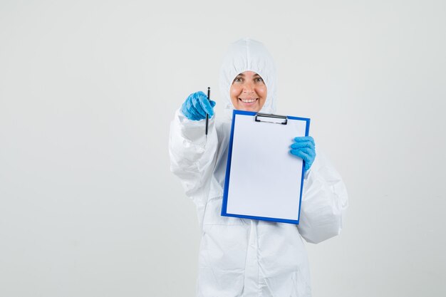 Foto gratuita medico femminile che mostra appunti e penna in tuta protettiva