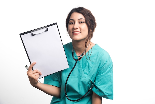白い背景の上のペンと聴診器で空のクリップボードを示す女性医師。高品質の写真