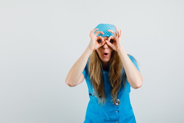 파란색 유니폼에 안경 제스처를 보여주는 여성 의사와 놀란 찾고