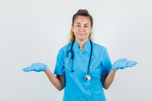 Female doctor showing helpless gesture in blue uniform