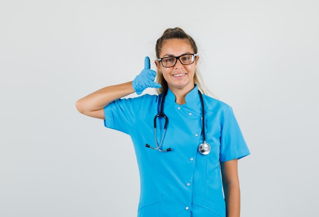 Женщина-врач показывает жест телефона в синей форме