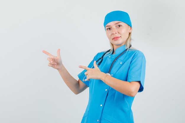 Female doctor showing pistol gesture and smiling in blue uniform