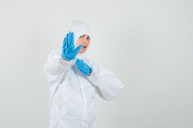 Female doctor showing stop gesture with hand on chest in protective suit