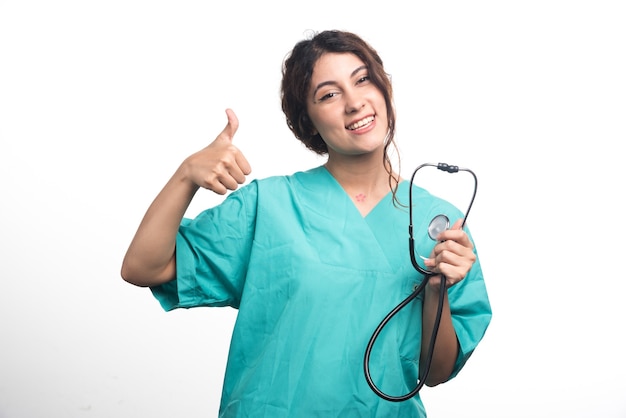 Женщина-врач показывает палец вверх на белом фоне. Фото высокого качества