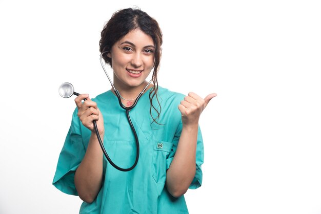Женщина-врач показывает палец вверх со стетоскопом на белом фоне