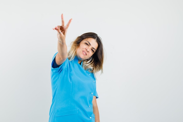 파란색 유니폼에 v 기호를 보여주는 여성 의사와 자신감을 찾고