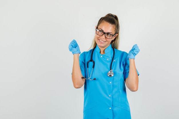 Medico femminile che mostra il gesto del vincitore in uniforme blu