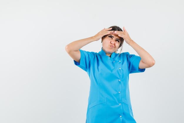 Medico femminile che schiaccia il brufolo sulla fronte in uniforme blu