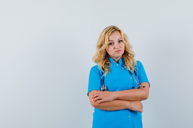 Dottoressa in piedi in uniforme blu e alla ricerca di uno spazio calmo per il testo