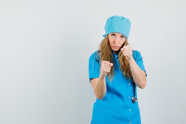 Female doctor standing in boxer pose in blue uniform and looking confident 