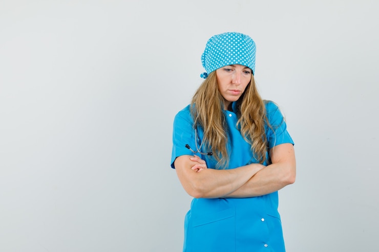 Free Photo female doctor standing with crossed arms in blue uniform and looking pensive. 