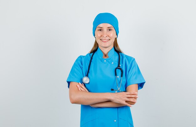 Female doctor standing with crossed arms in uniform and looking glad