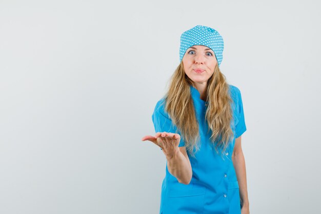 Female doctor stretching hand in questioning gesture in blue uniform 