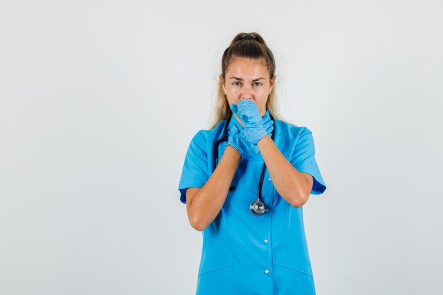 青い制服を着た咳に苦しんでいる女性医師