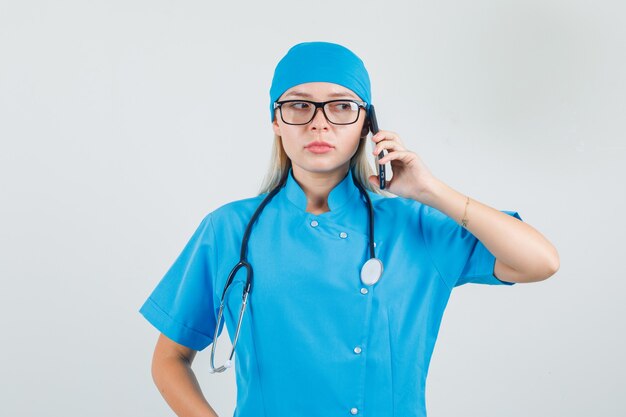 Female doctor talking on smartphone in blue uniform