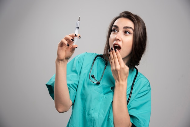 Female doctor in uniform scared of a syringe.