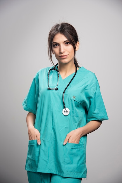 Female doctor in uniform standing on gray