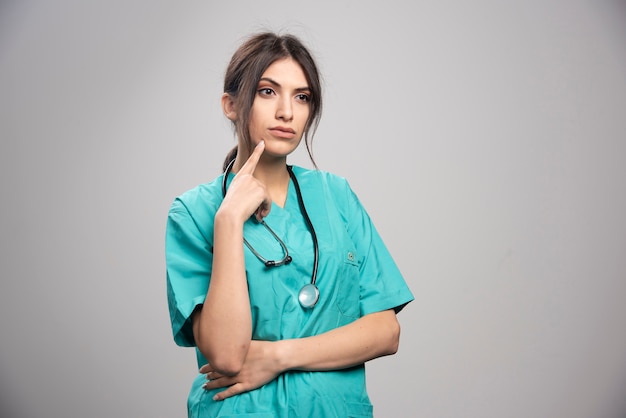 Free photo female doctor in uniform standing on gray