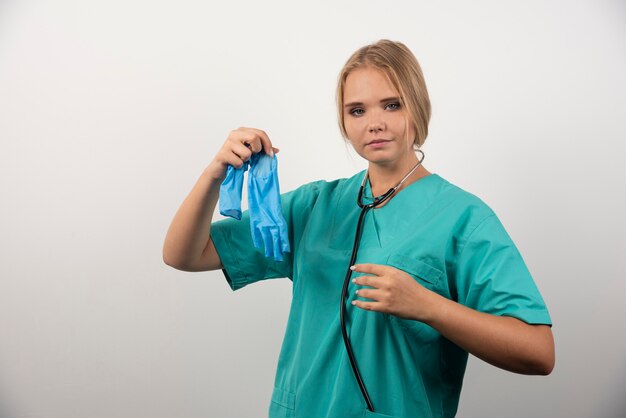 Женщина-врач в форме с медицинскими перчатками.