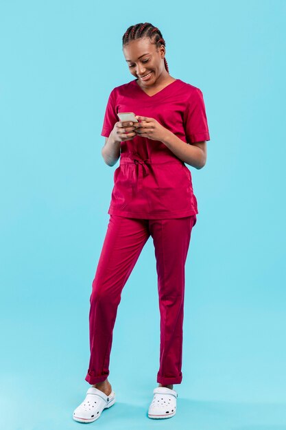 Female doctor using the phone next to blue wall