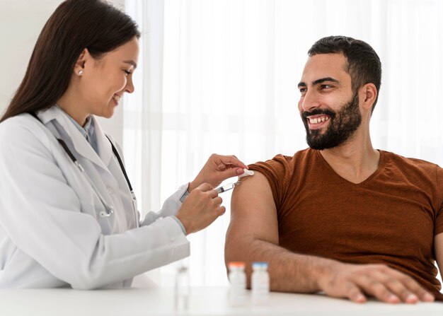 Female doctor vaccinating a handsome man