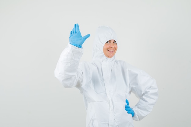 Foto gratuita medico donna agitando la mano per il saluto in tuta protettiva