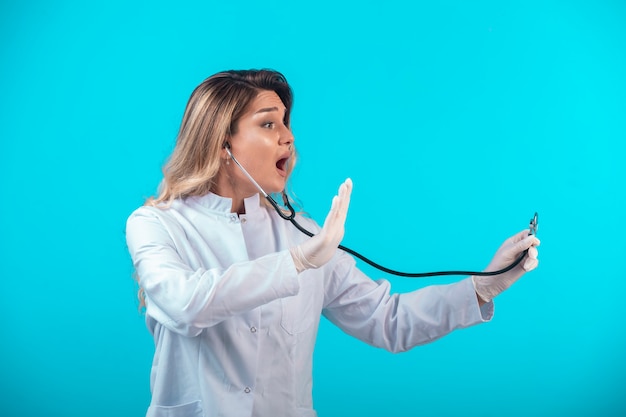 Foto gratuita medico femminile in uniforme bianca che controlla con lo stetoscopio.